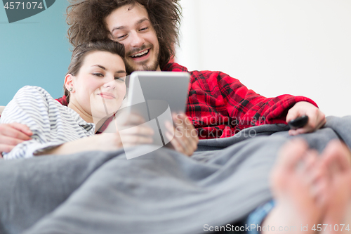 Image of couple relaxing at  home with tablet computers