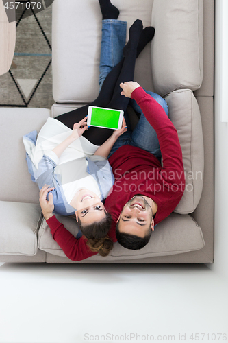 Image of couple relaxing at  home with tablet computers