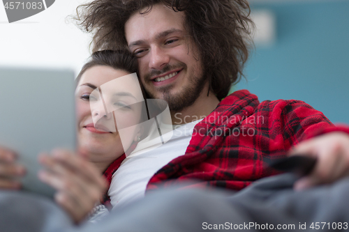 Image of couple relaxing at  home with tablet computers