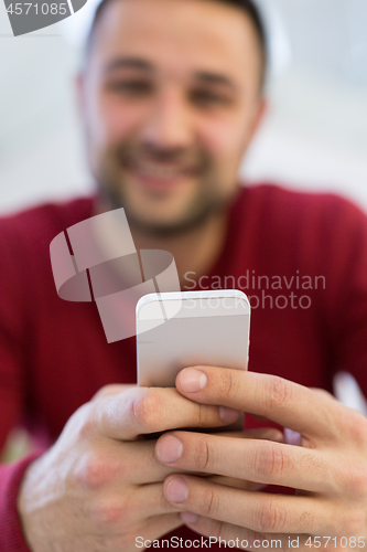 Image of young man using a mobile phone  at home