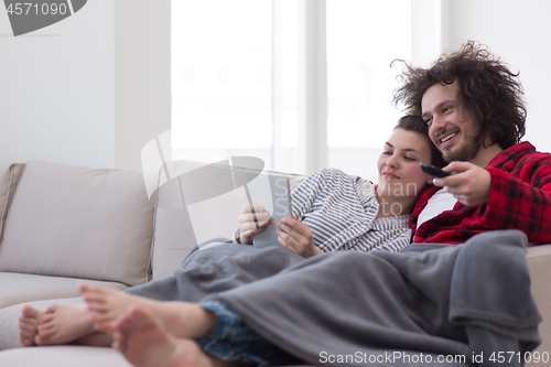 Image of couple relaxing at  home with tablet computers