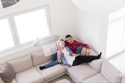 Image of couple relaxing at  home with tablet computers