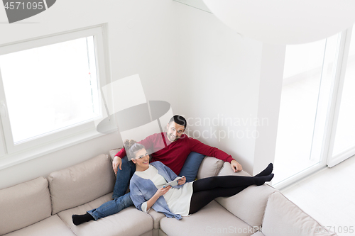 Image of couple relaxing at  home with tablet computers