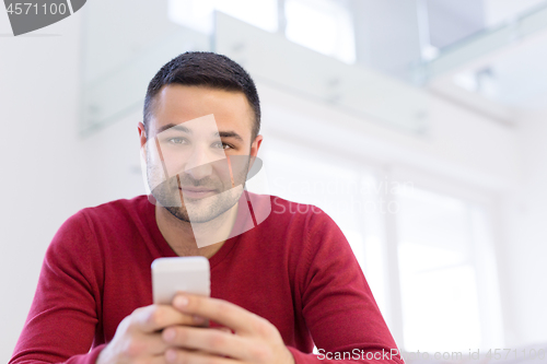 Image of young man using a mobile phone  at home