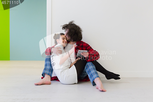 Image of Young Couple using digital tablet on the floor