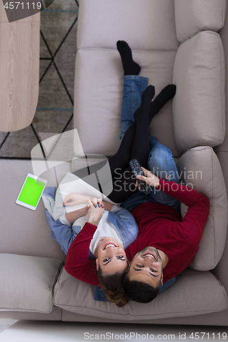 Image of Young couple on the sofa watching television top view