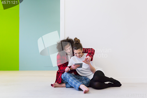 Image of Young Couple using digital tablet on the floor