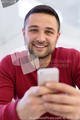 Image of young man using a mobile phone  at home