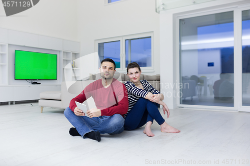 Image of Young Couple using digital tablet on the floor