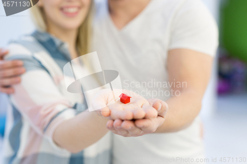 Image of couple showing small red house in hands