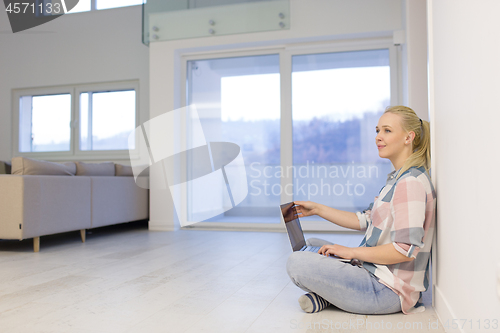 Image of young woman using laptop computer on the floor