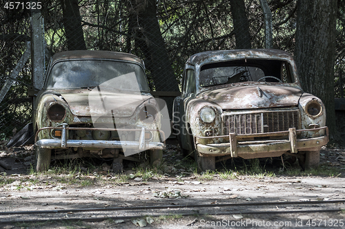 Image of Two old, rusted, abandoned cars.