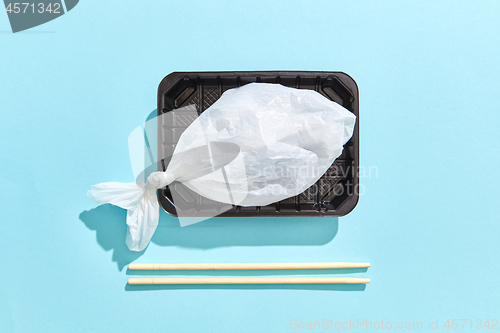 Image of Dinner container with fish from plastic bag served wooden chopsticks.