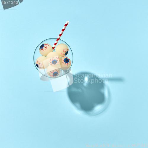 Image of Halloween glass with cocktail with eyeballs and plastic straw.