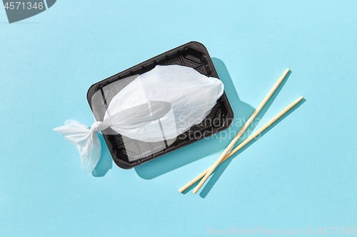 Image of Plastic bag in a shape of fish on a plastic plate with chopsticks.