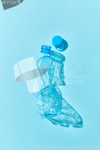 Image of Empty used plastic bottle on a blue background with shadows.