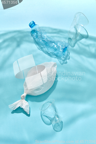 Image of Ocean waves from shadows of plastic foil with floating bottle, fish and cups.