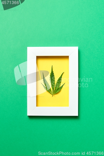 Image of Creative yellow handmade frame with cannabis leaf on a green background.