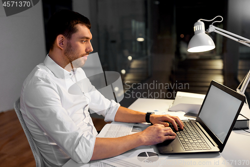 Image of businessman with laptop working at night office