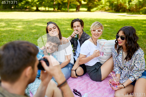 Image of friends with drinks photographing at summer picnic