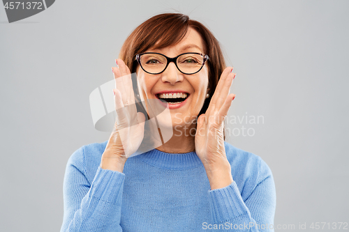 Image of senior woman in glasses calling over grey