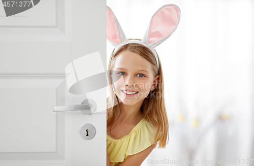 Image of happy girl with easter bunny ears peeking out door