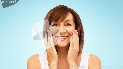 Image of portrait of smiling senior woman touching her face