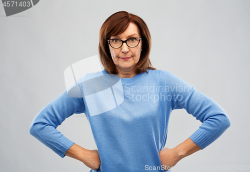 Image of angry senior woman in glasses over grey background