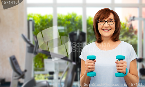 Image of senior woman with dumbbells exercising in gym