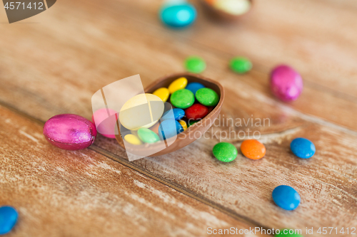 Image of chocolate egg and candy drops on wooden table