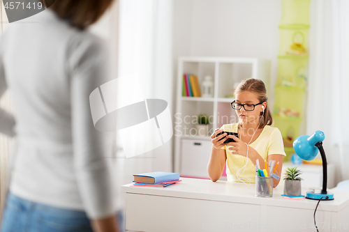 Image of girl listening to music and mother entering room