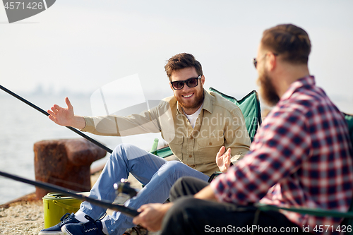 Image of happy male friends with rods talking about fishing