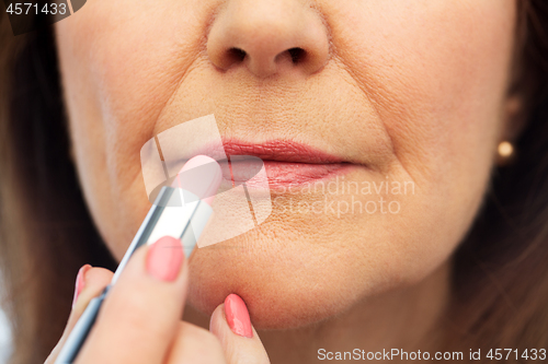 Image of close up of senior woman applying lipstick