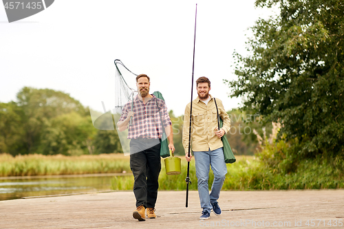 Image of friends with fishing rods and net at lake or river