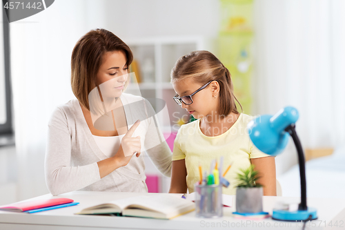 Image of strict mother talking to daughter doing homework