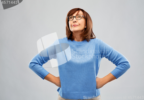 Image of displeased senior woman in glasses over grey