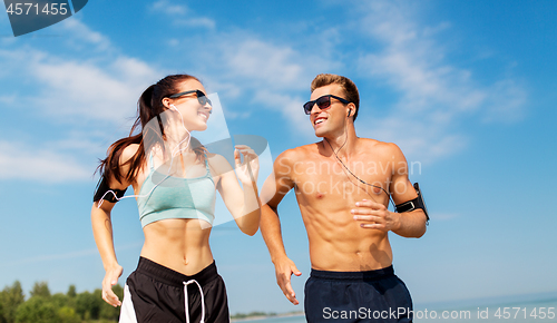 Image of couple with phones and arm bands running on beach