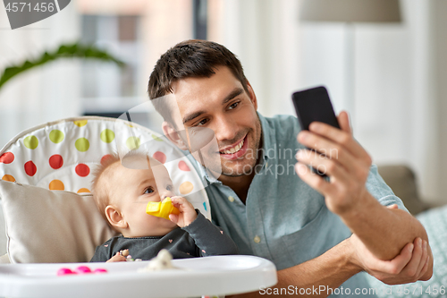 Image of father with baby daughter taking selfie at home