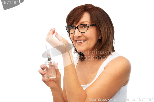 Image of senior woman smelling perfume from her wrist