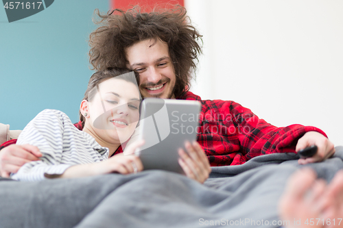 Image of couple relaxing at  home with tablet computers