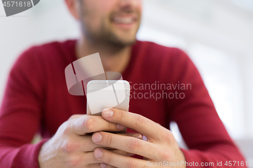 Image of young man using a mobile phone  at home