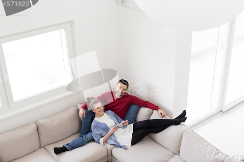 Image of couple relaxing at  home with tablet computers