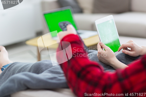 Image of couple relaxing at  home with tablet computers