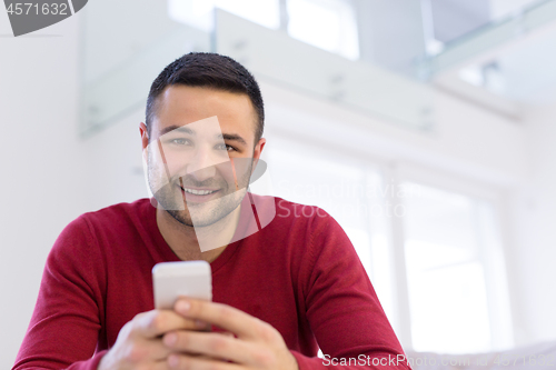 Image of young man using a mobile phone  at home