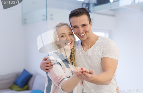 Image of couple showing small red house in hands