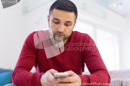 Image of young man using a mobile phone  at home