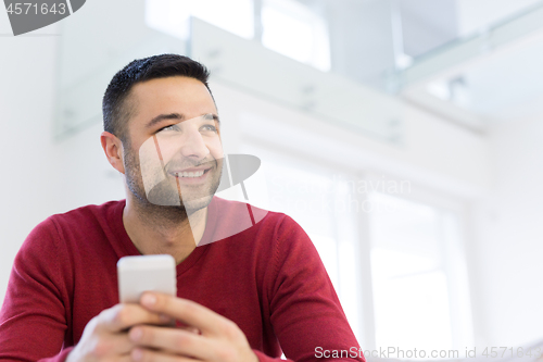 Image of young man using a mobile phone  at home