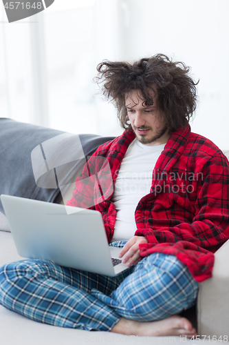 Image of man freelancer in bathrobe working from home