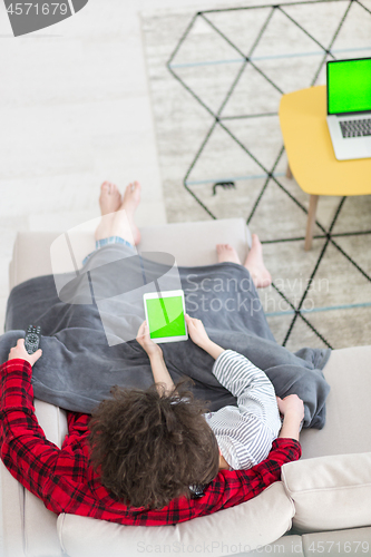 Image of couple relaxing at  home with tablet computers