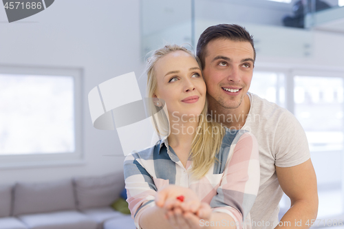 Image of couple showing small red house in hands